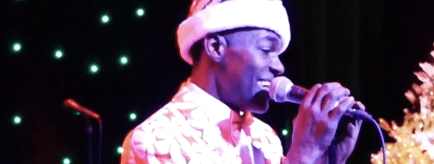 Singer wearing Santa hat, performing on stage.
